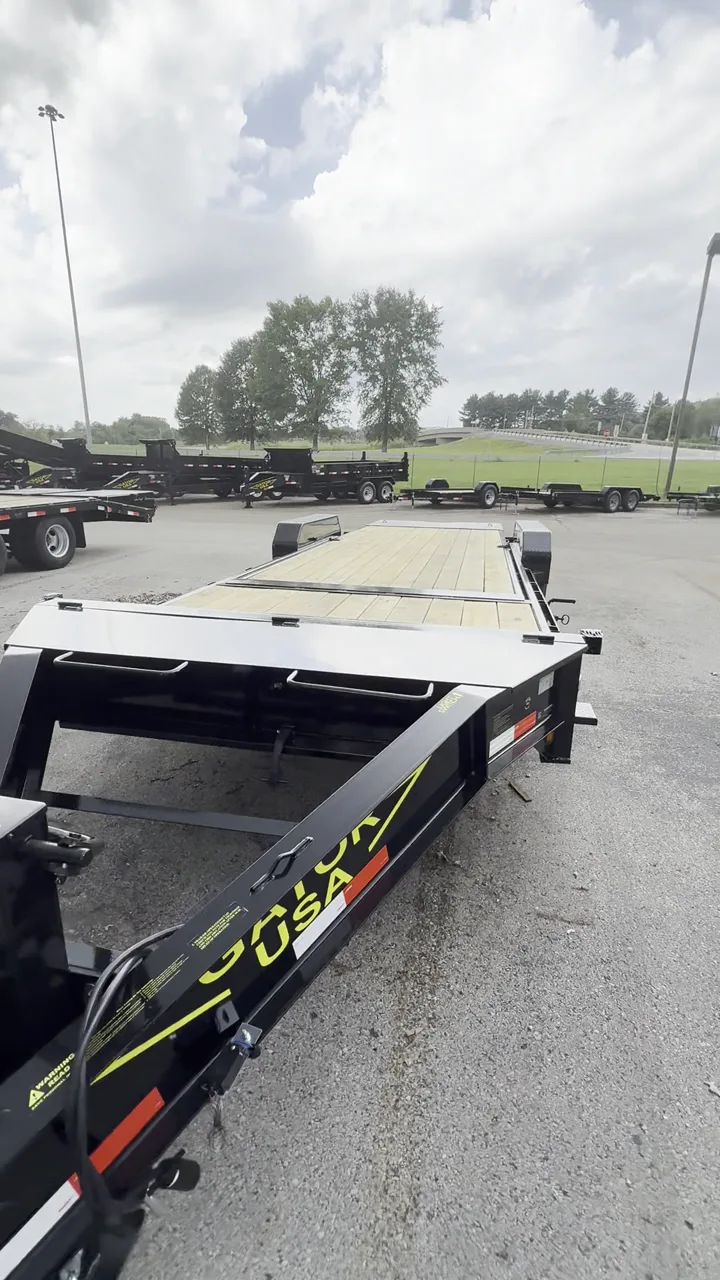 Black Gatormade Aardvark tilt-deck trailer with a wood deck, parked on the factory lot